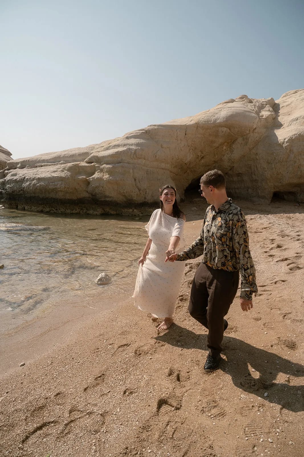 Couple running on beach — joyful Cyprus wedding moment