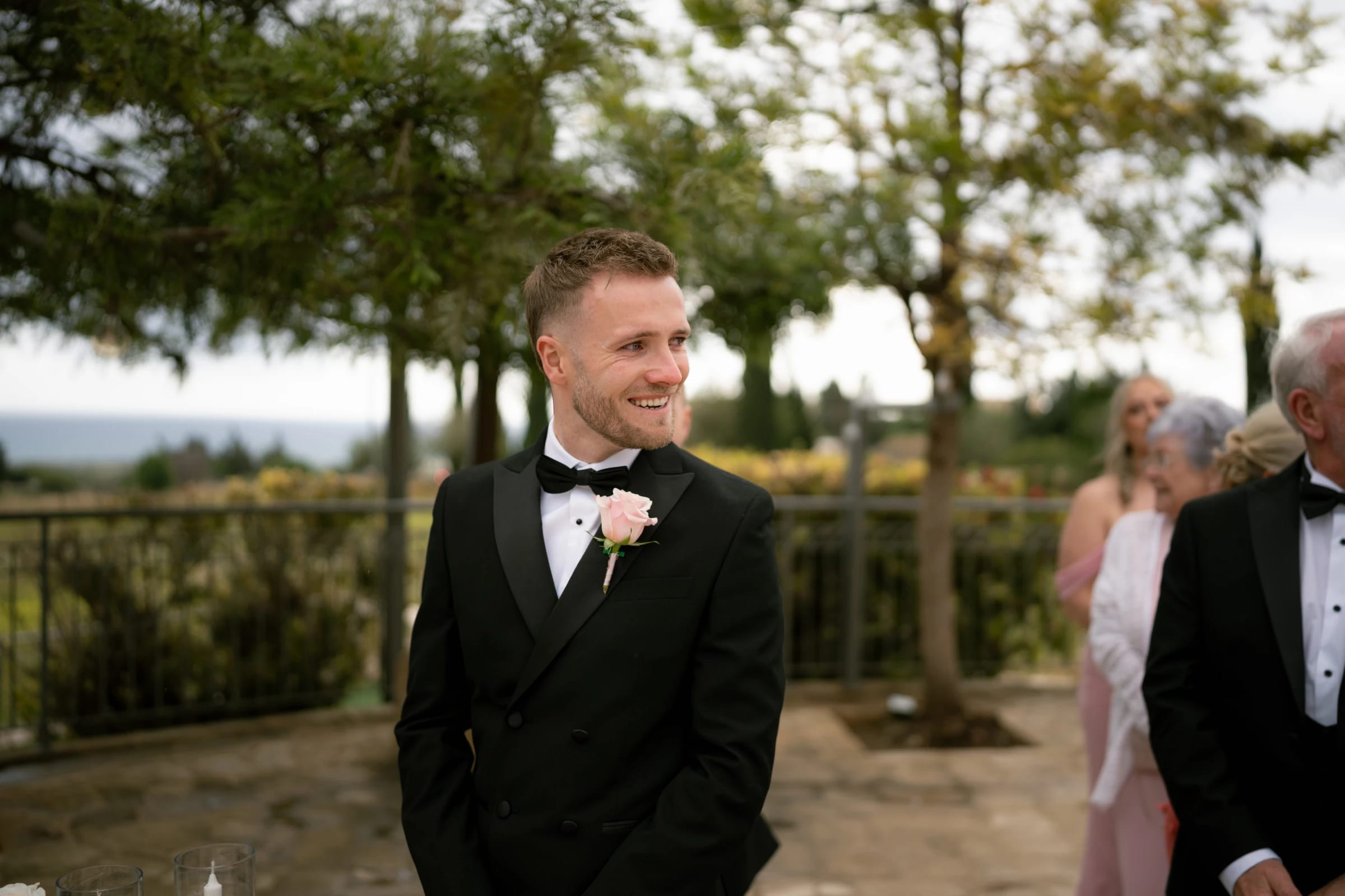Groom Daniel smiling as he waits at the ceremony at Liopetro wedding venue, Paphos.