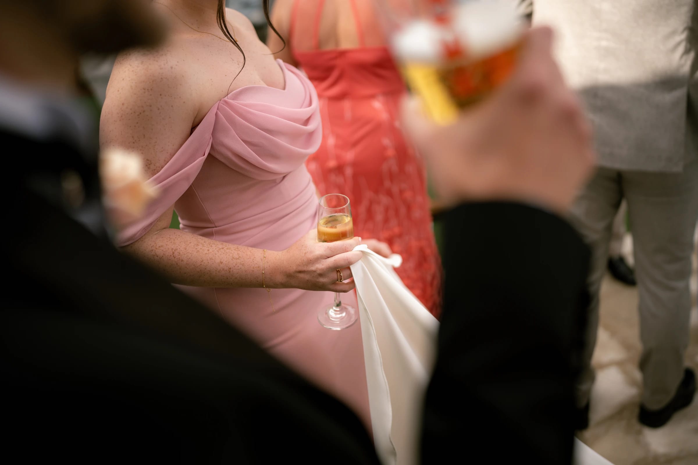 Bridesmaid in pink dress holding a champagne flute during cocktail hour at Liopetro, Kouklia, Paphos.