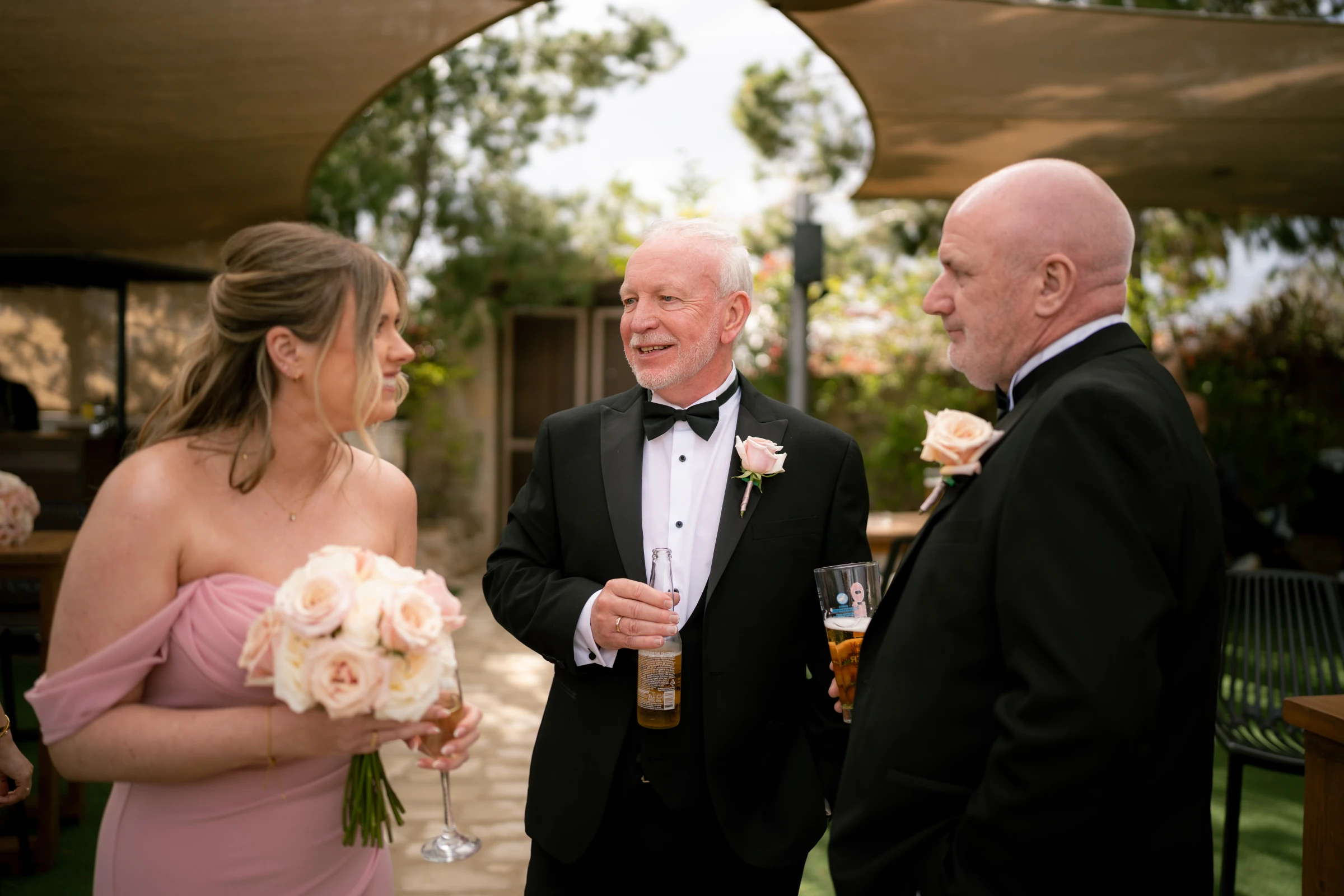 Bridesmaid talking with the fathers of the bride and groom during drinks at Liopetro wedding venue, Paphos.