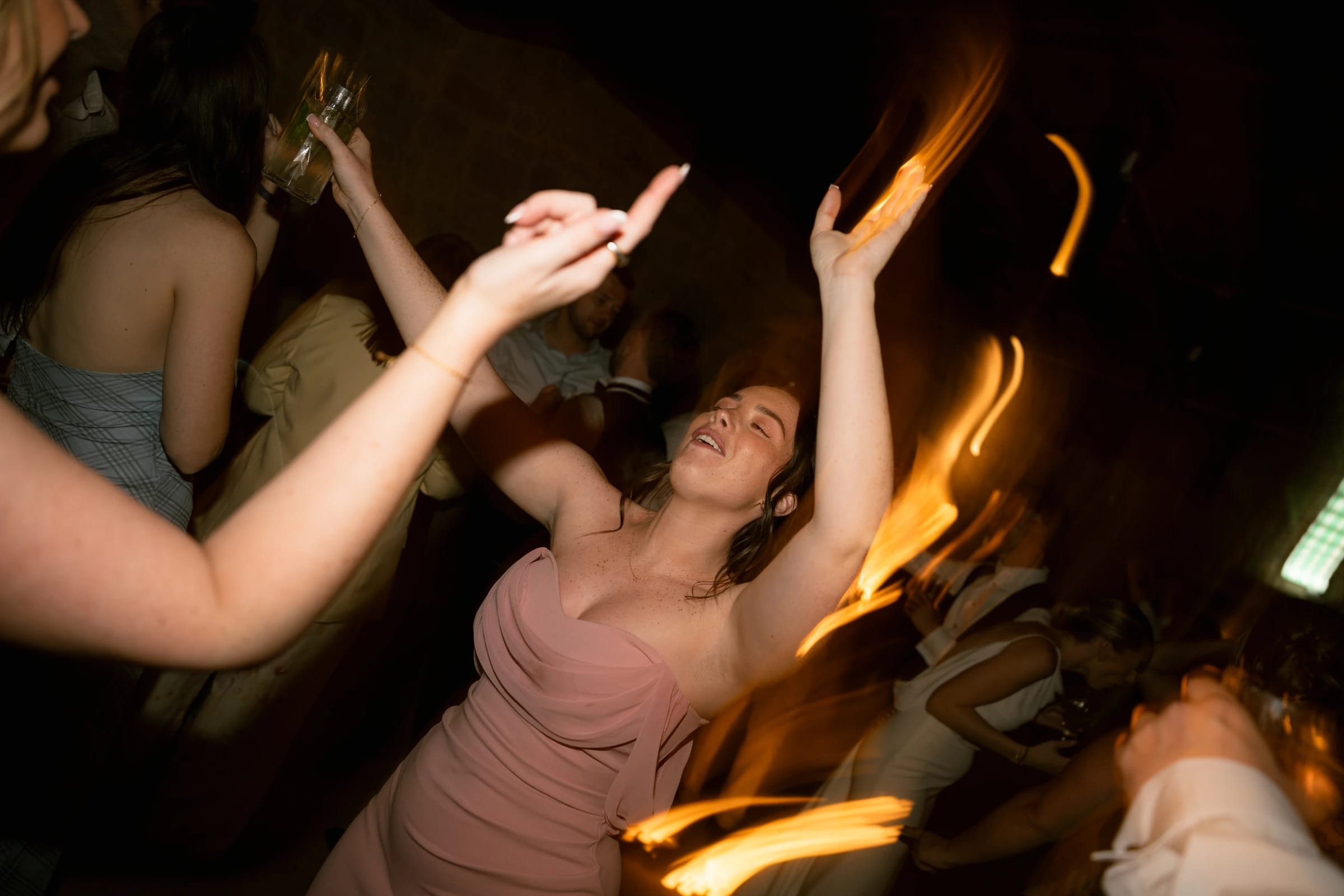 Bridesmaid in pink dress dancing under the lights at the Liopetro wedding reception, Kouklia, Paphos.