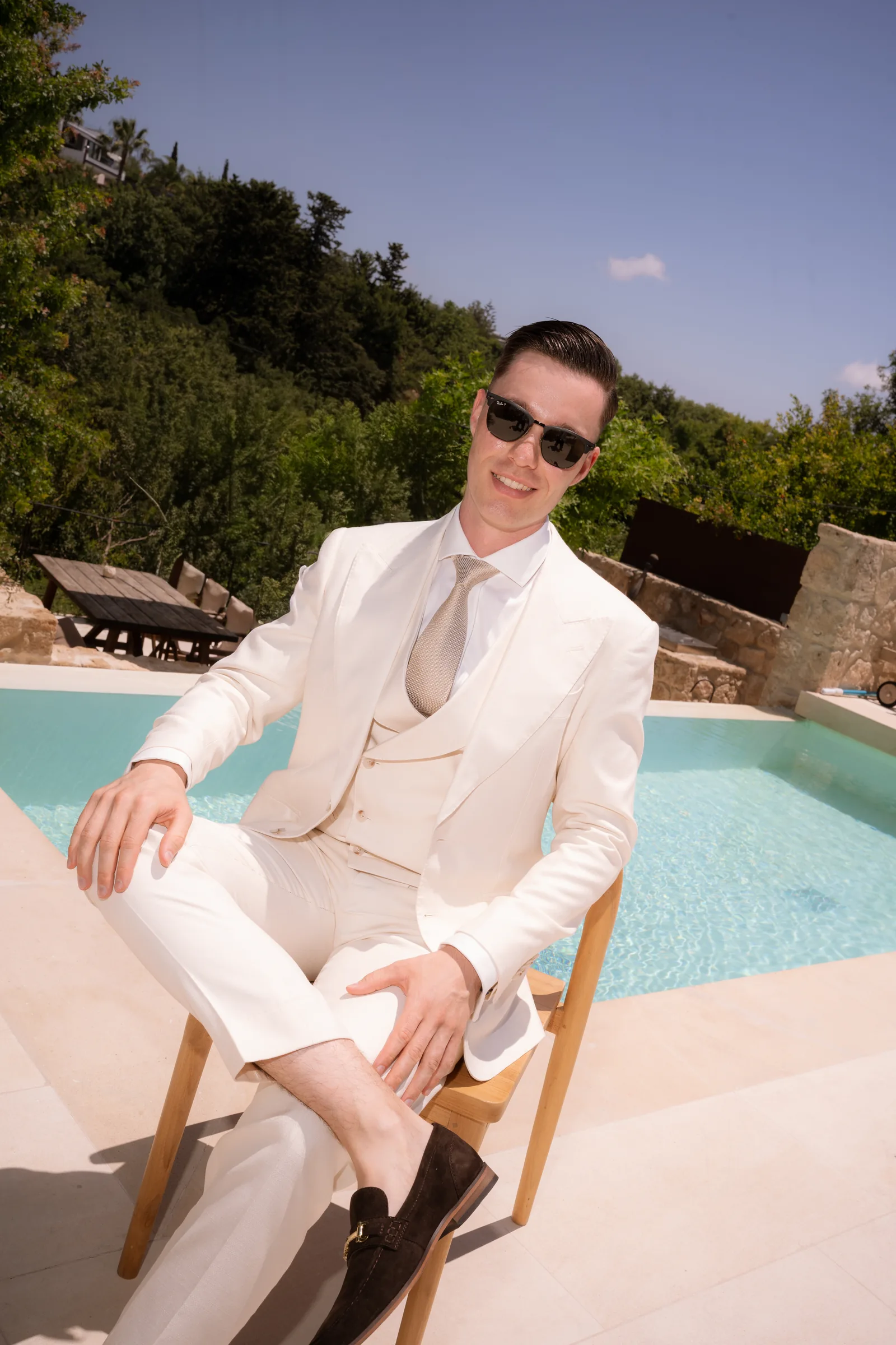 Frank seated in his cream suit and sunglasses beside the plunge pool during preparations at Liopetro, Paphos.