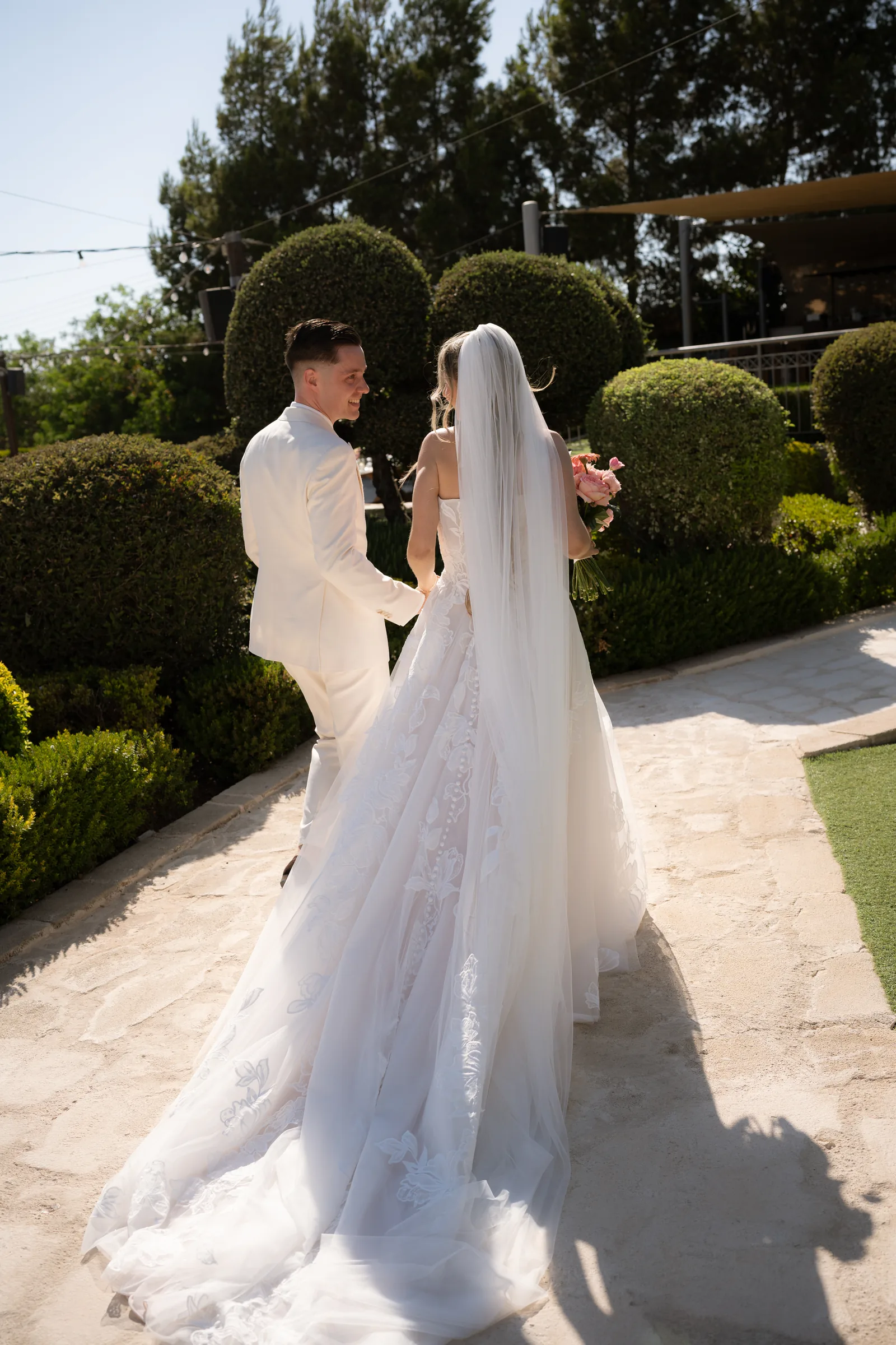 Frank and Franziska walking hand in hand away through the clipped box gardens after their ceremony at Liopetro, Kouklia, Paphos.