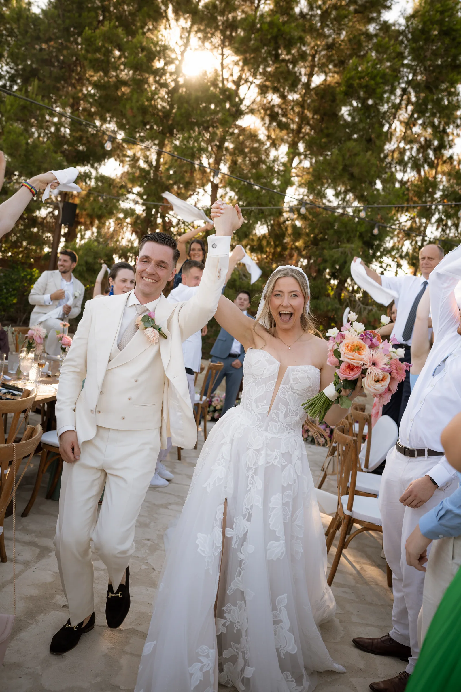 Franziska laughing with delight as she and Frank enter through a tunnel of guests waving napkins at sunset, Liopetro, Kouklia, Paphos.