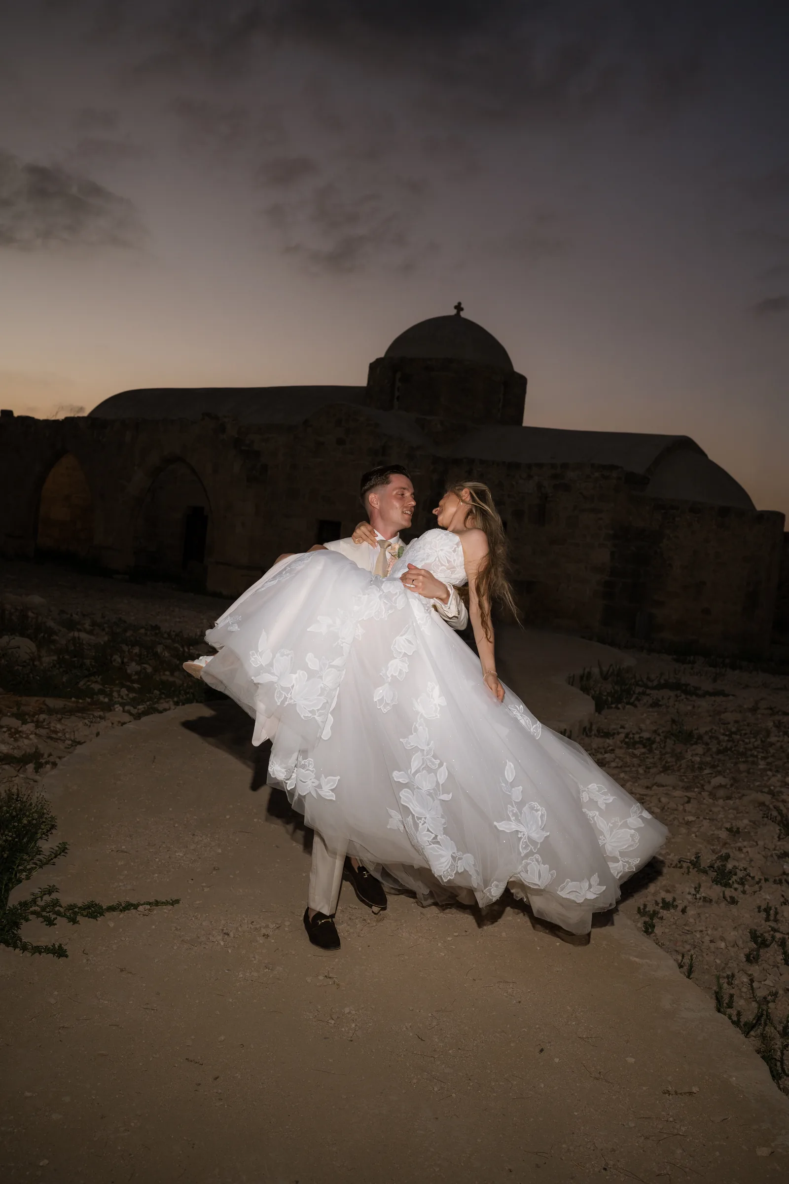 Frank and Franziska embracing on the headland with the last light over Aphrodite's Rock, Paphos.