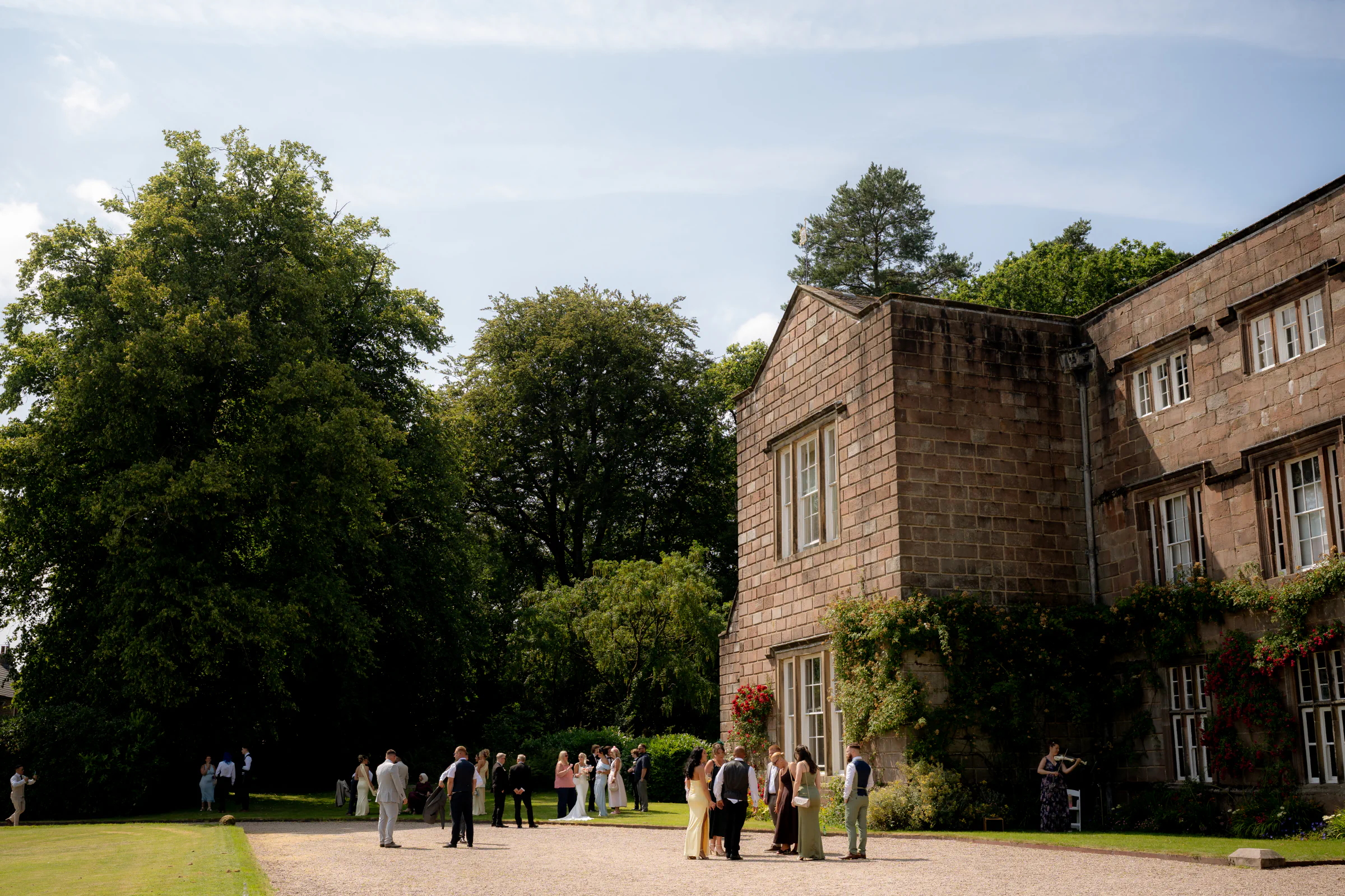 Guests gathering on the lawn beside Browsholme Hall after Josh and Ellie's outdoor wedding ceremony in Lancashire.