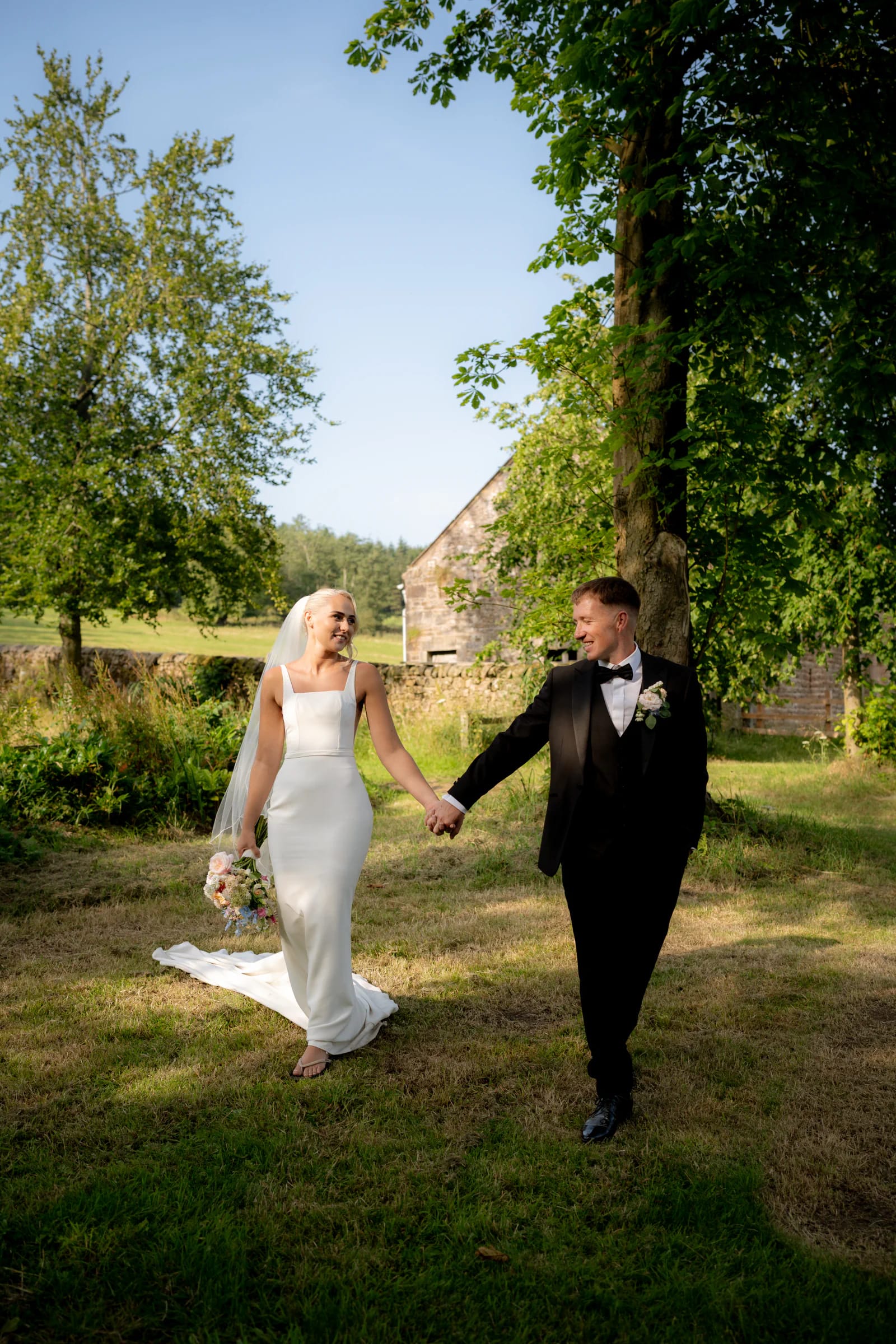 Josh and Ellie walking through the Browsholme Hall grounds in the late-afternoon light