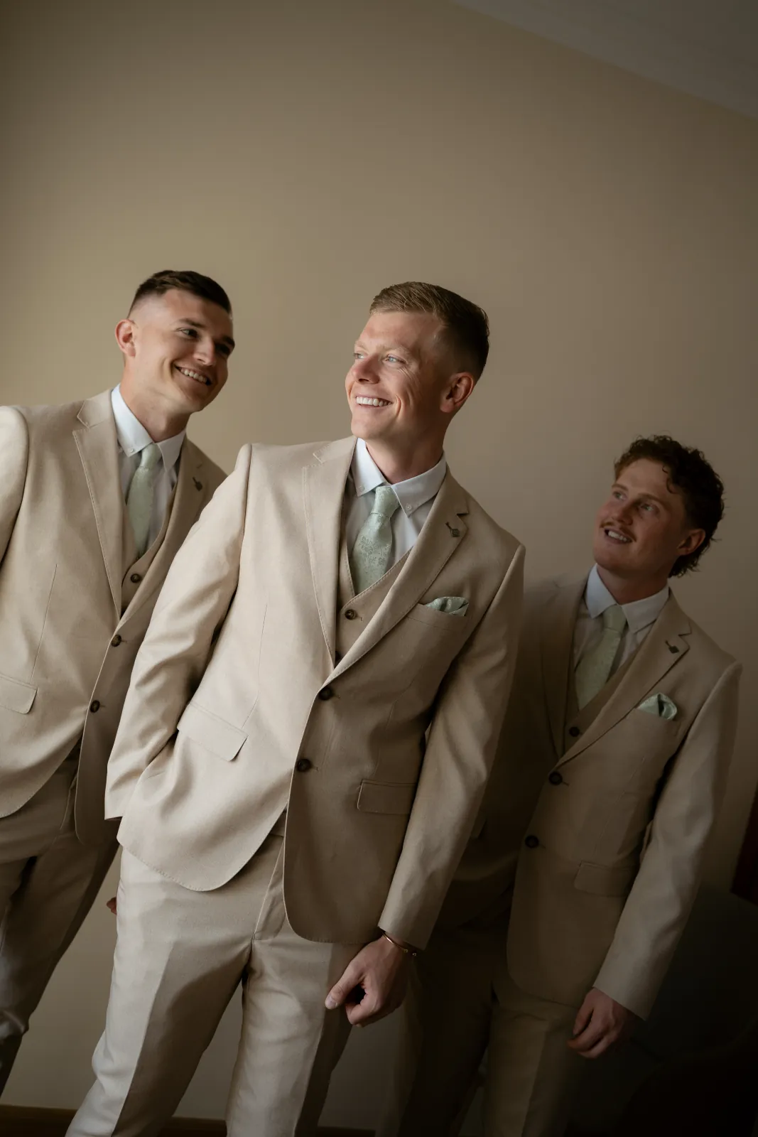 Aaron laughing with his groomsmen in sand-coloured suits before the ceremony at Coral Residences, Paphos.