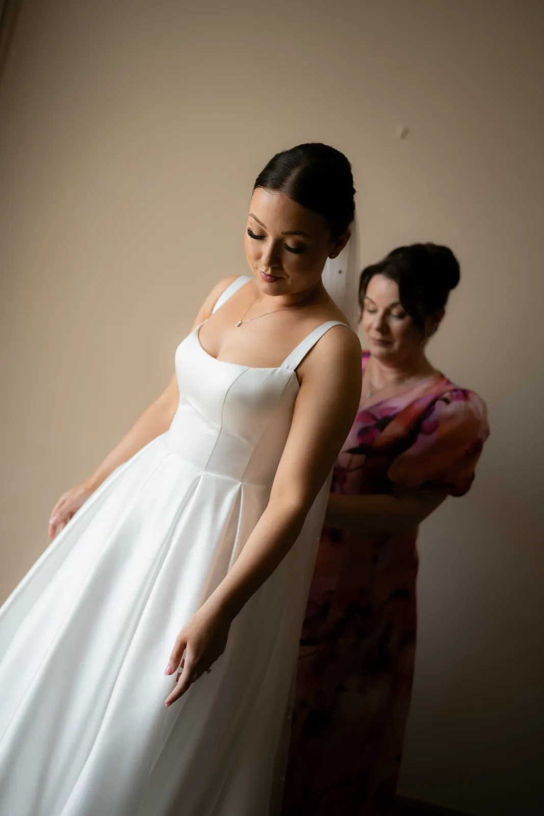 Sian stepping into her square-necked wedding gown with her mother's help during preparations near Paphos, Cyprus.