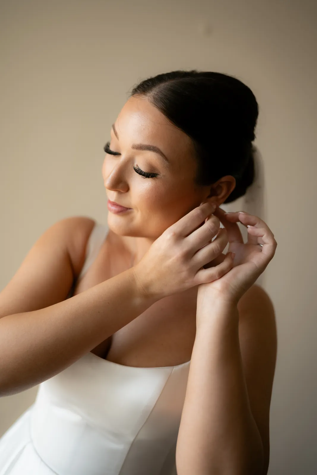 Sian fastening an earring, her hair in a low chignon, during bridal preparations before her Coral Residences wedding, Paphos.