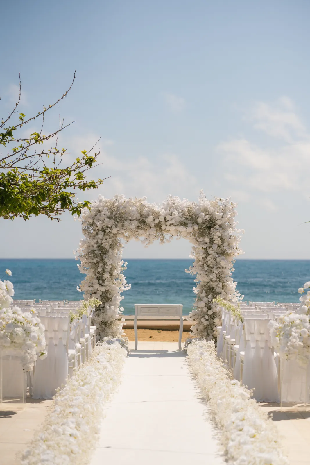 White aisle runner lined with flowers leading to the floral arch and the Mediterranean at Coral Residences, Paphos.