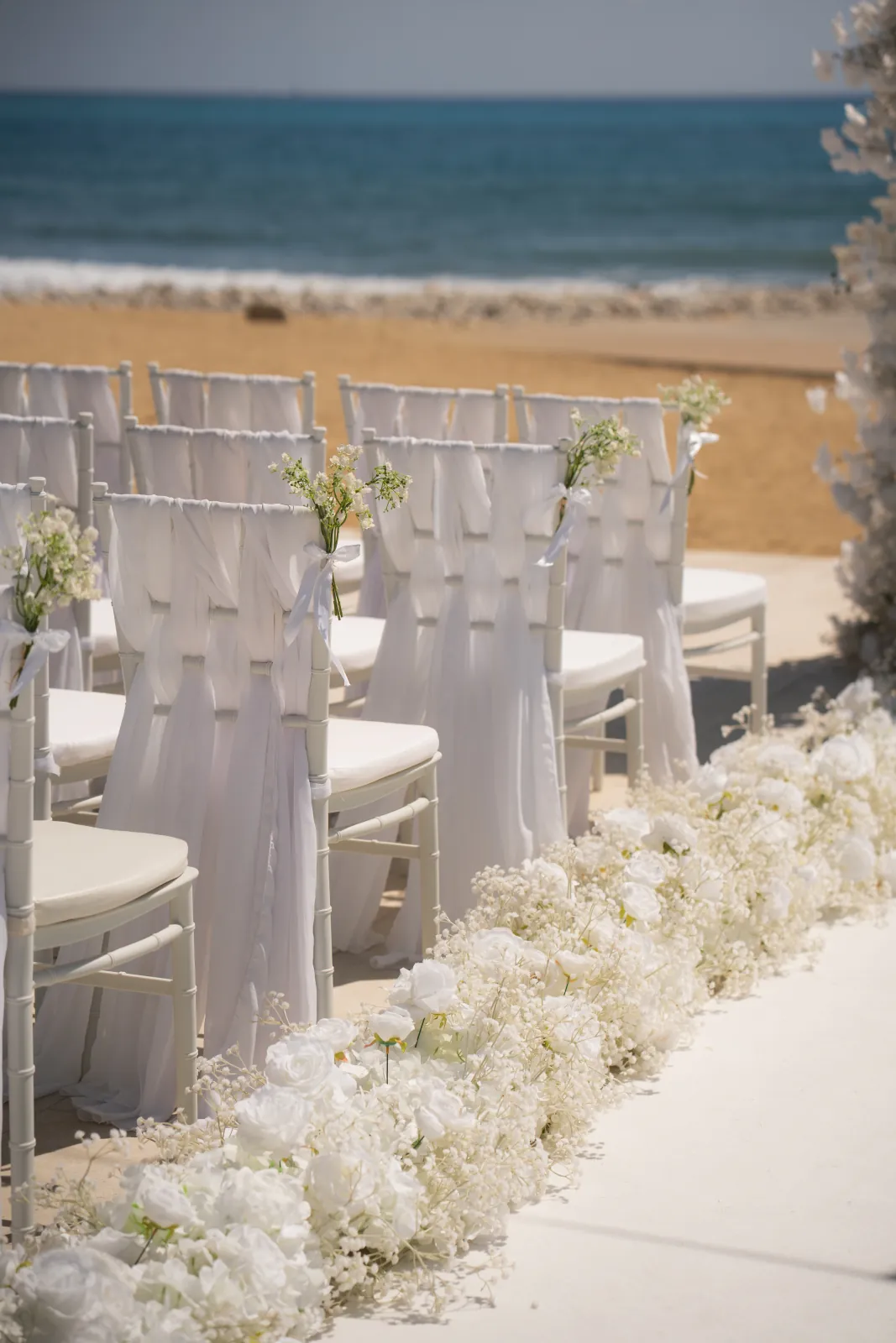 White draped chairs tied with baby's breath overlooking the beach at Coral Residences, Paphos, Cyprus.