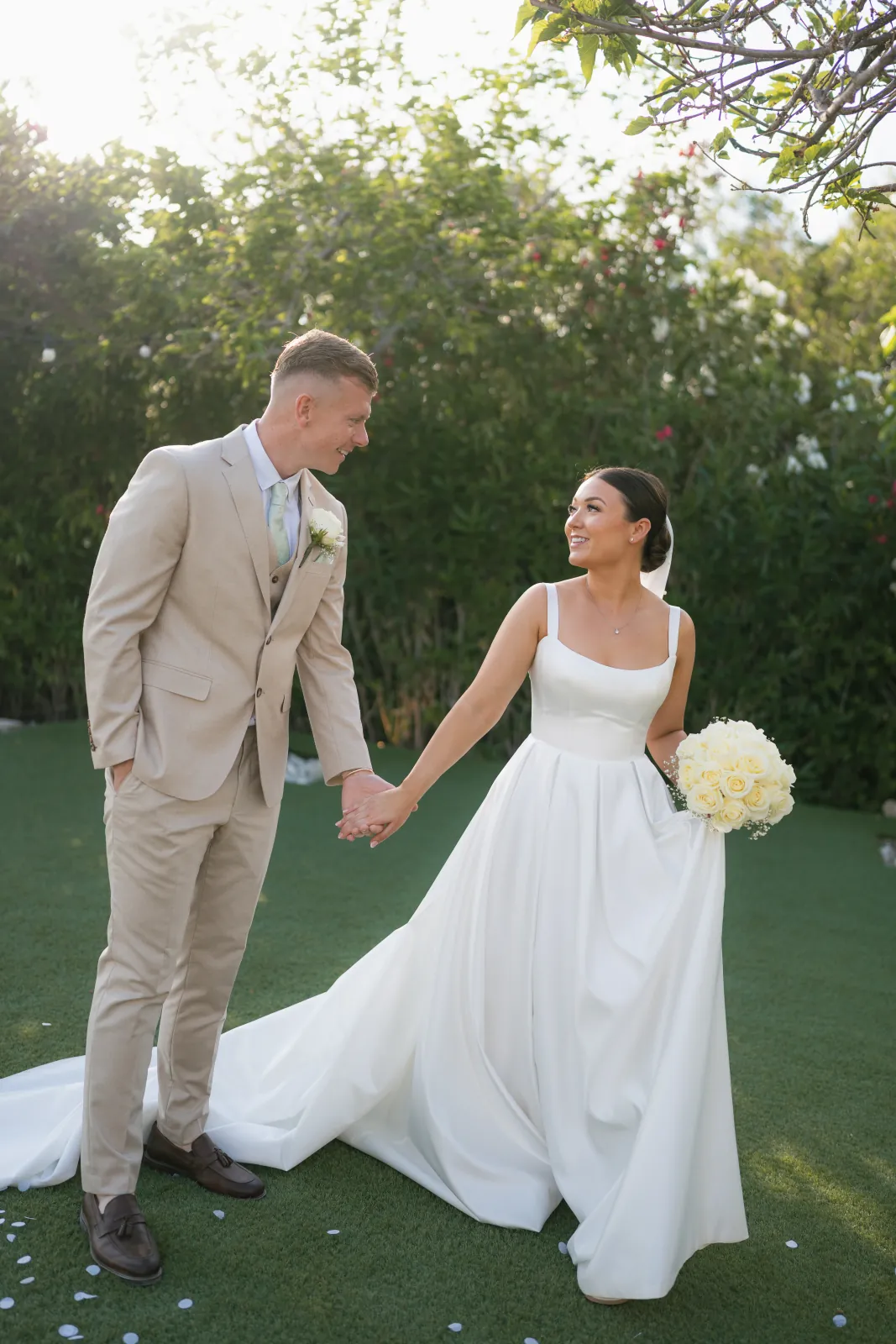 Bride and groom holding hands in the gardens at Coral Residences, Paphos, Cyprus
