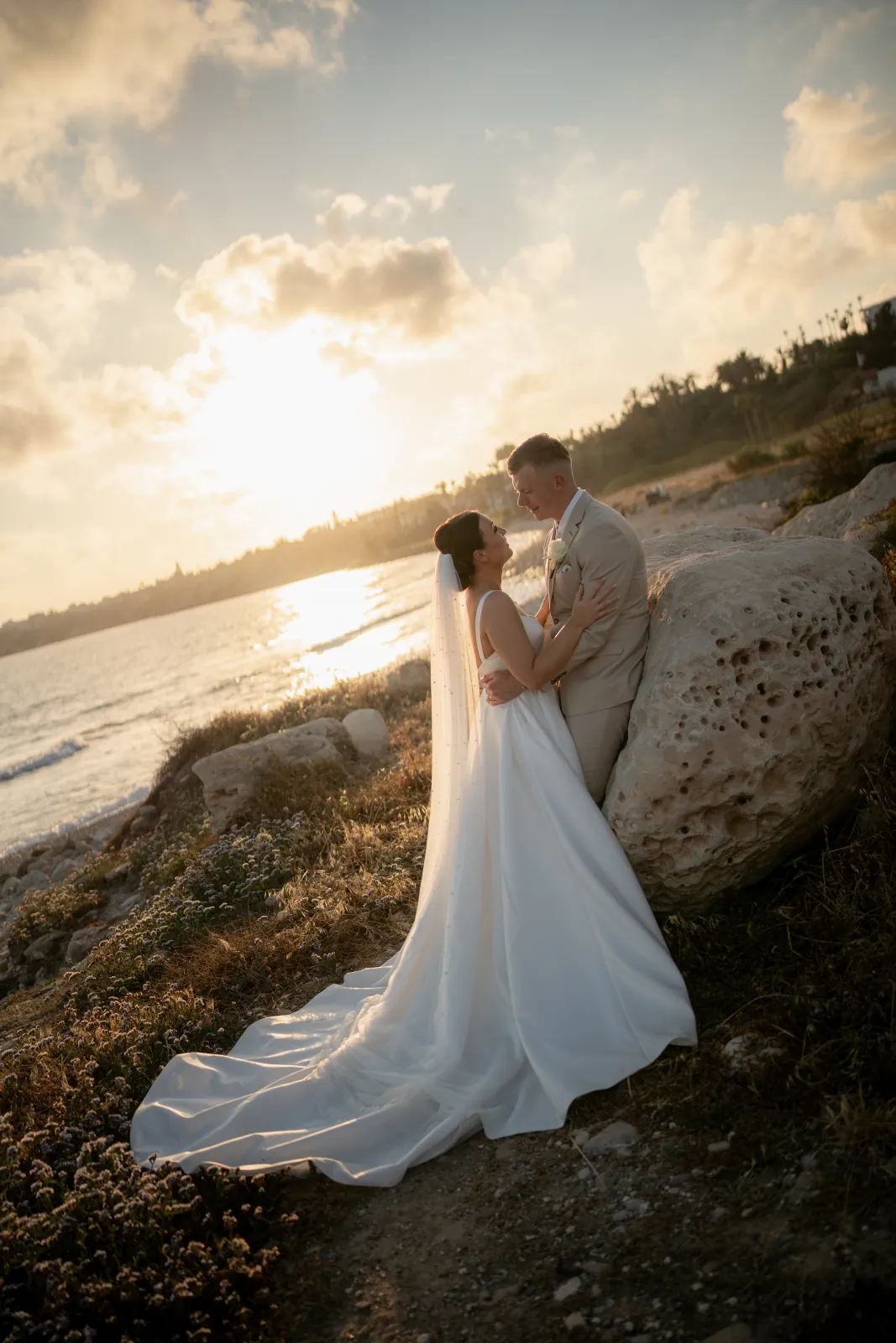 Sian and Aaron at golden hour on the rocky shoreline as the sun sets over the sea at Coral Residences, Paphos, Cyprus.